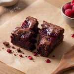 Raspberry jam brownie broken open on parchment paper showing the fudgy chocolate centre and raspberry jam swirl.